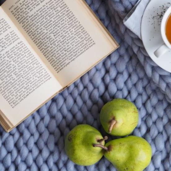 Bord med en bog, en kop the og tre pærer