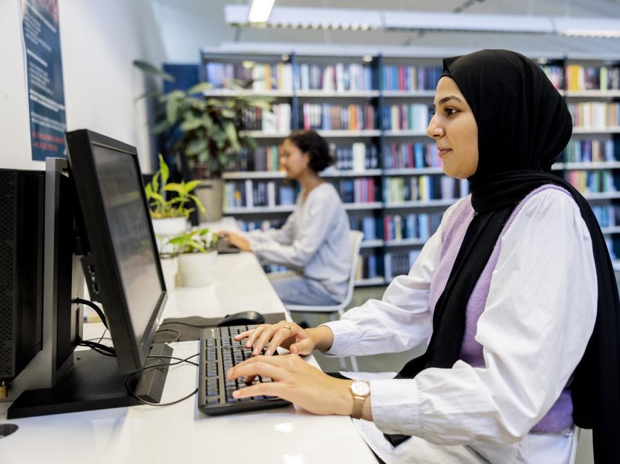 Person arbejder ved en biblioteks pc.